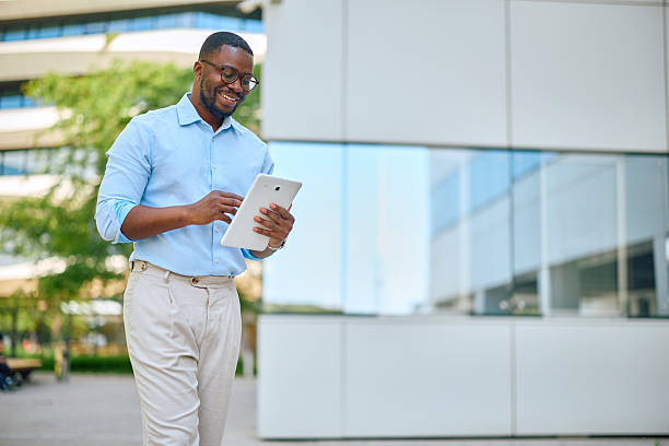 istock Smiling businessman using digital tablet while walking near office building 2214889169