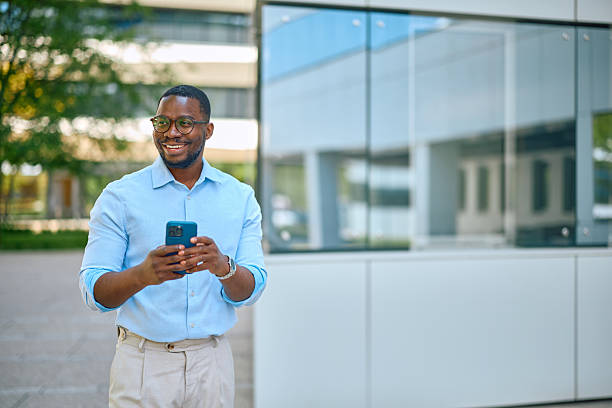 istock Smiling businessman using smartphone outside office building 2214889170