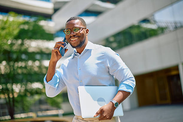 istock Smiling businessman walking and talking on the phone while holding a laptop 2214889222