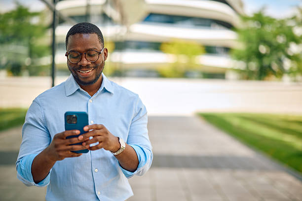 istock Smiling businessman using smartphone outside modern office building 2214889589