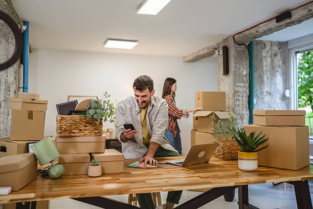 istock man use mobile phone while woman hold and unpack boxes at new place 2214890355