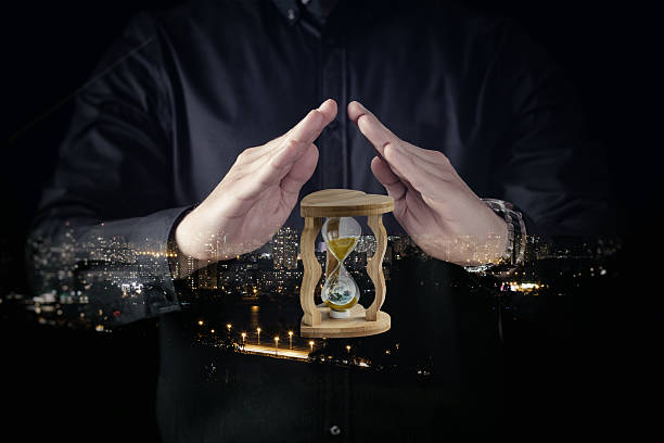 istock Man holds hourglass with city lights in background 2214896466