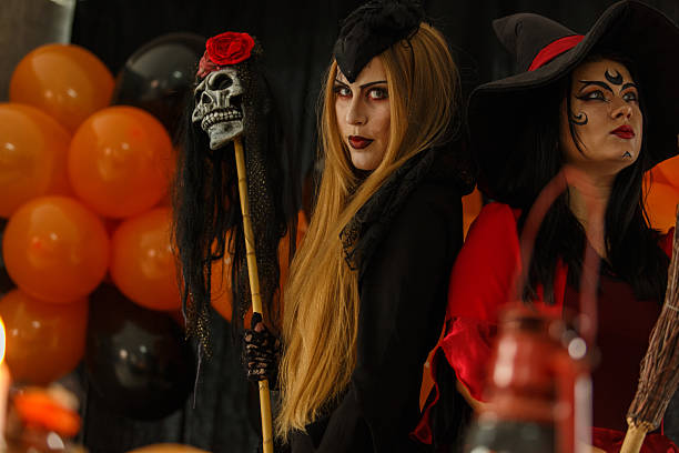A beautiful young Asian woman dressed as a witch holds an orange pumpkin,celebrating Halloween joyfully against a clean white background, radiating festive spirit,happiness,and playful holiday charm