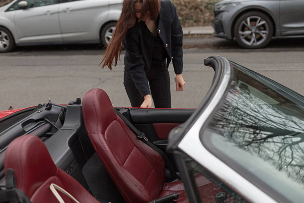 istock A woman is currently standing next to a shiny red convertible car 2214904182