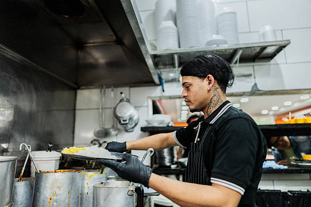 istock Young man serving food in a restaurant kitchen 2214908661
