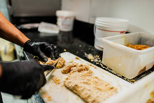 istock Close-up of chef man cutting a raw breaded chicken at restaurant kitchen 2214908683