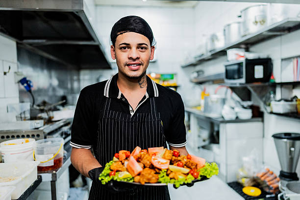 istock Portrait of young chef man holding platter with breaded chicken at restaurant kitchen 2214908736