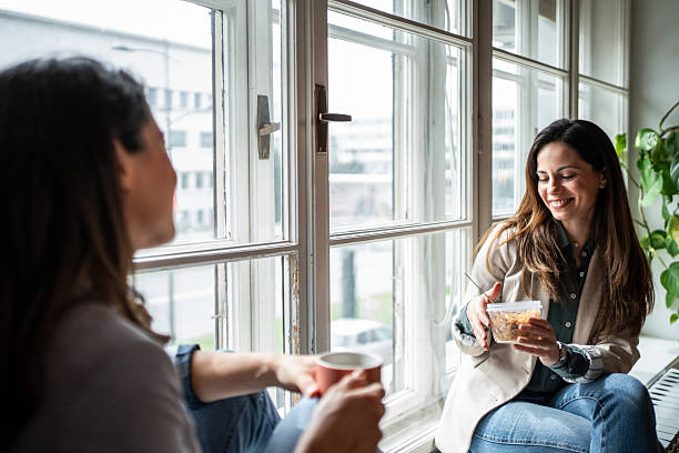 istock Two businesswomen enjoying lunch break by the window 2214908889