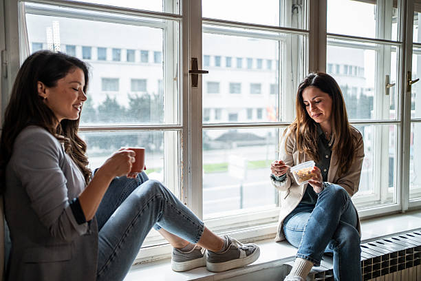 istock Two young businesswomen taking a break and chatting by the window 2214908926