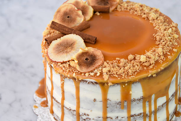 istock Caramel Fig Drip Cake featuring layers of moist cake drizzled with rich caramel, topped with dried fig slices, and chopped nuts isolated on grey background closeup side view of baked cafe dessert 2214910645