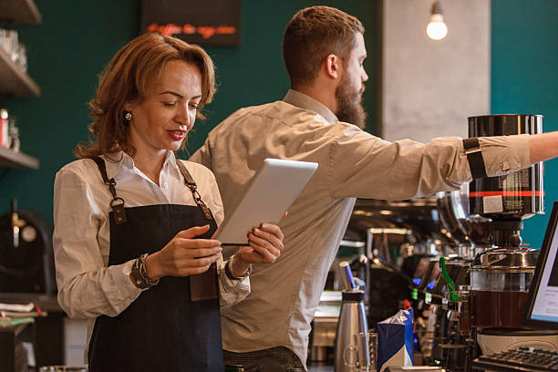 istock Barista using tablet while working in a busy coffee shop environment 2214911425