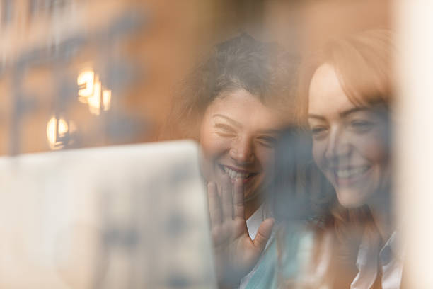 istock Two smiling women interacting through a webcam in front of a laptop screen. 2214911508