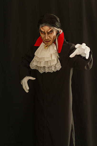 Mysterious man in vampire costume posing against black background stock photo