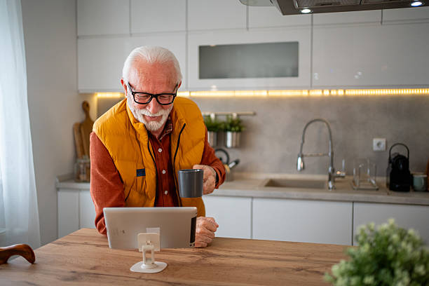 istock Senior man enjoying morning coffee and using digital tablet in kitchen 2214915046