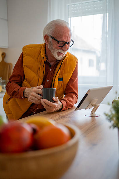 istock Senior man enjoying coffee and using digital tablet in kitchen 2214915083