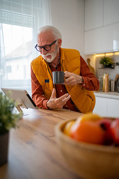 istock Senior man enjoying a video call with coffee in his kitchen 2214915086