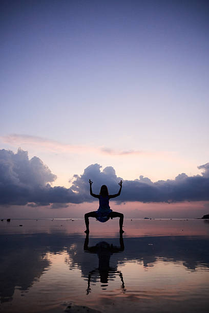 istock Woman practicing yoga on a reflective beach during a peaceful sunset 2214918313