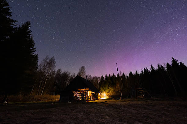 istock A secluded log cabin in the forest at night, illuminated from within, under an impressive starry sky with a hint of aurora. 2214919486