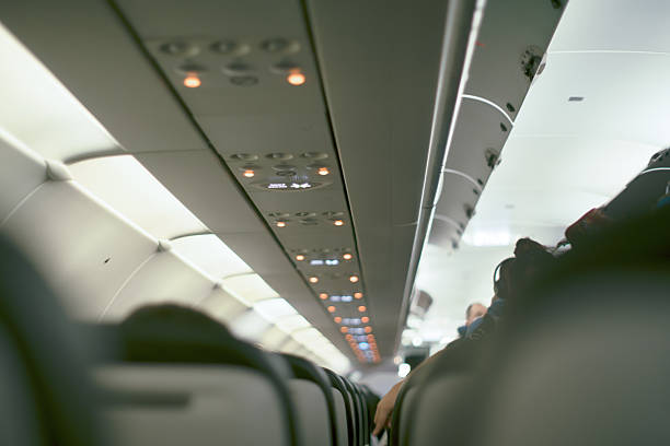 istock Interior of a commercial airplane featuring empty rows of seats and overhead compartments illuminated by ambient lighting. 2214920372