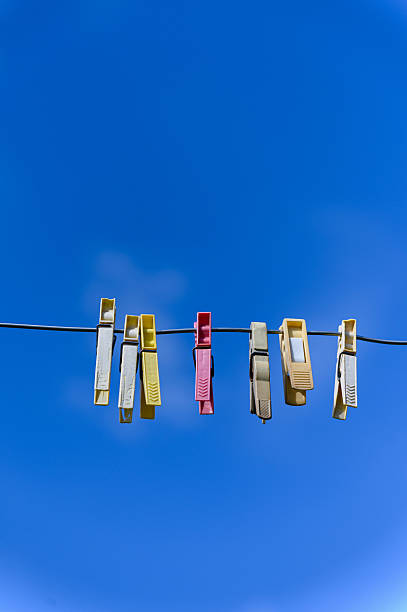 istock Colorful clothespins hanging on wire against blue sky. 2214922984