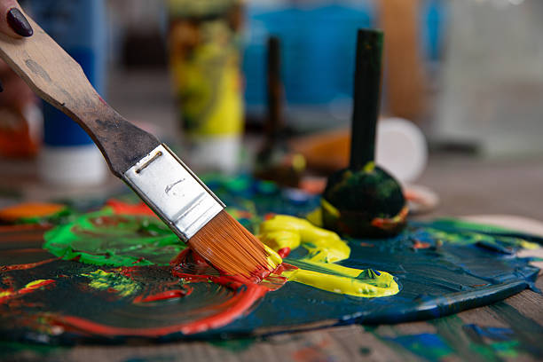 A detailed closeup of a painters rich palette showcasing an array of vivid colors and brushes used for art