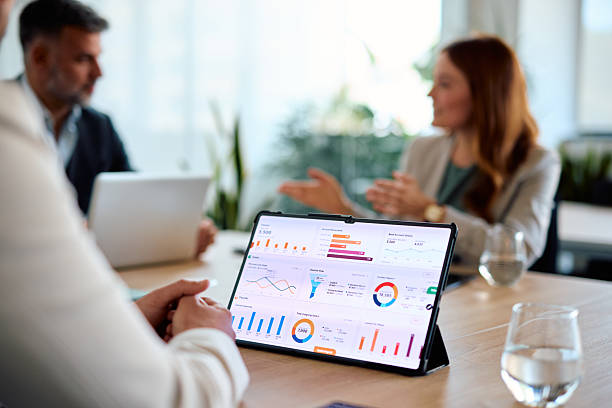 Business colleagues are having a discussion about financial data displayed on a digital tablet during a productive meeting in a modern office
