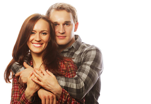 Full length of happy young couple standing while looking at each other against plain background