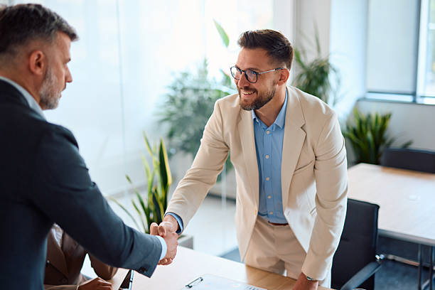 istock Two businessmen shaking hands after successful meeting in modern office 2214925766