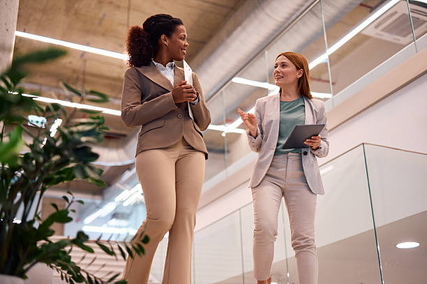 istock Businesswomen walking and talking in modern office building 2214925769