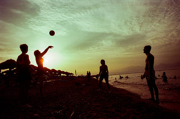 Schiavonea, Calabria, Italy– 07 July 2024: A group of friends playing volleyball on the beach during sunset.