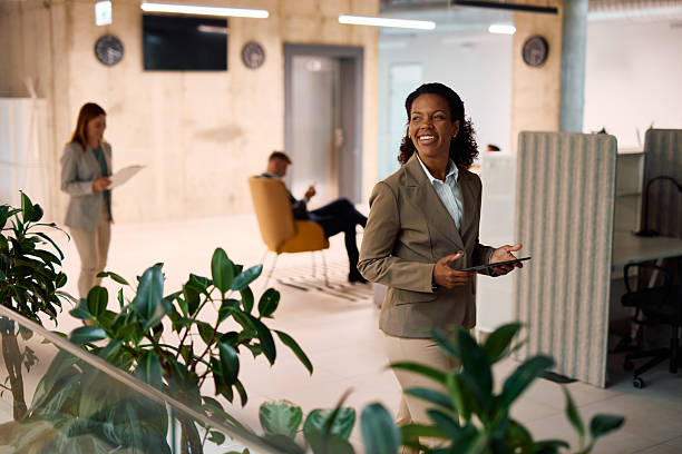 istock Smiling manager walking in modern office holding tablet 2214926218