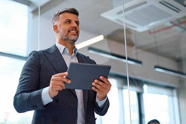 istock Confident businessman holding digital tablet and looking away in office 2214928550