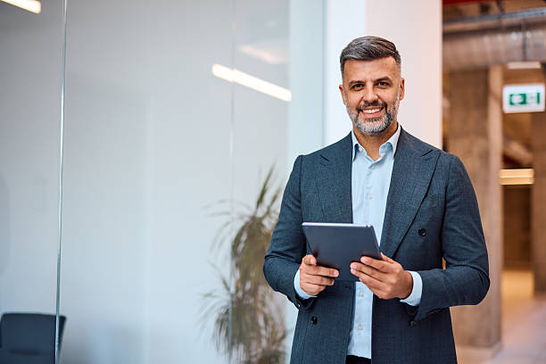 istock Smiling businessman holding digital tablet in modern office 2214928568