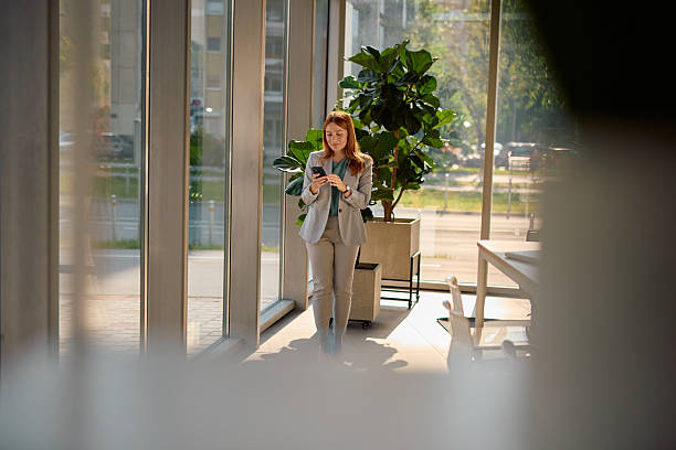 istock Businesswoman walking in modern office using smartphone 2214928979