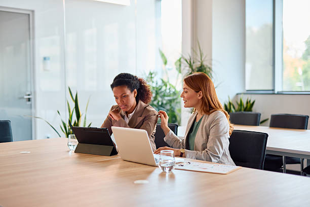 istock Businesswomen collaborating on a project using laptop and tablet in modern office 2214928997