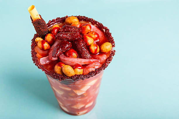 Crazy little glass, a mixture of sweet, salty and spicy ingredients. Typical snack from Mexico Crazy little glass, a mixture of sweet, salty and spicy ingredients isolated on blue background. Typical snack from Mexico. candy mexican culture mexican cuisine peanut stock pictures, royalty-free photos & images