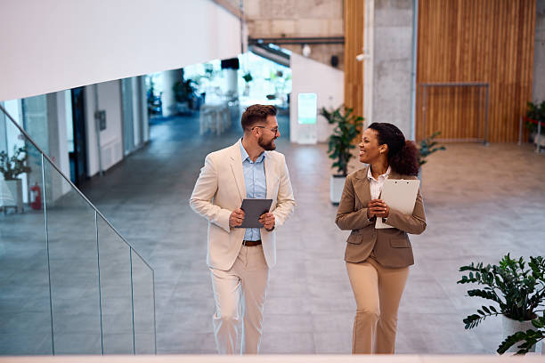istock Business partners walking and talking in modern office building lobby 2214929663