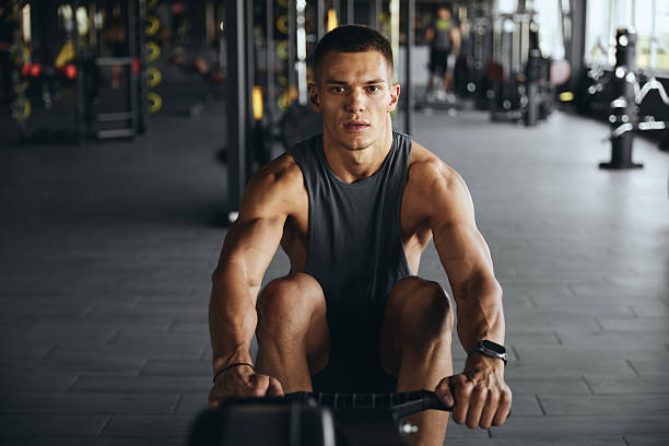 istock Fit young man works out on a rowing machine at the modern gym 2214929888