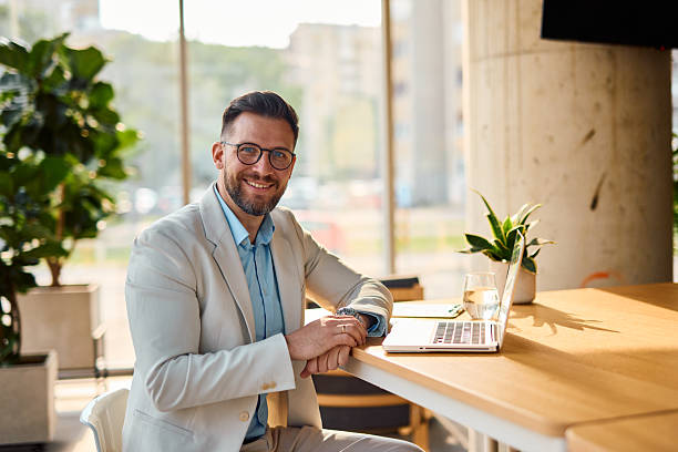 istock Businessman smiling while working with his laptop in a modern office 2214929970