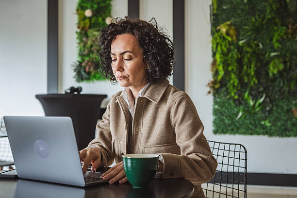 istock One mature woman working on laptop at cafe 2214932671