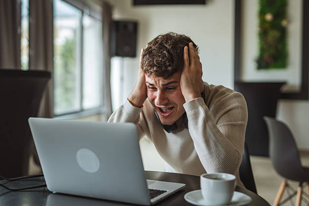 istock One man working on laptop and holding his head / negative emotions 2214932828