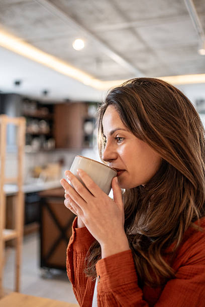 istock Serene woman enjoying a warm beverage in a modern kitchen 2214935679