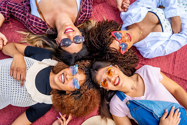 istock Four young women lying down on a blanket wearing sunglasses and smiling 2214938072