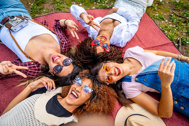 istock Four young women lying on blanket taking selfie and gesturing peace sign 2214938079