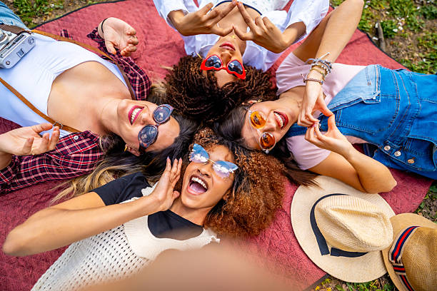 istock Four young women taking a selfie lying on a blanket making heart shapes 2214938097
