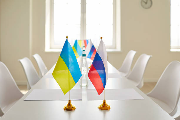 istock Table with Ukrainian and Russian flags in empty conference room before negotiation 2214938328