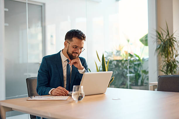 istock Smiling businessman working on laptop in modern office 2214938895