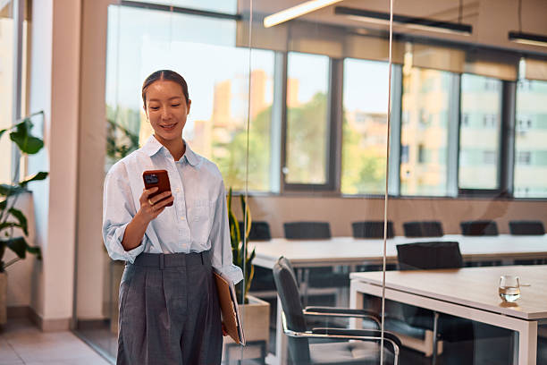 istock Young Asian businesswoman using smartphone in modern office 2214939312