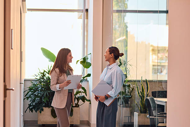 istock Two businesswomen discussing work in modern office corridor 2214939318