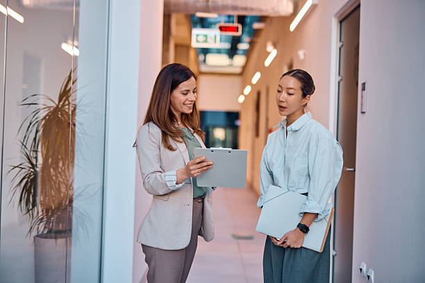 istock Two businesswomen discussing a document in office corridor 2214939414